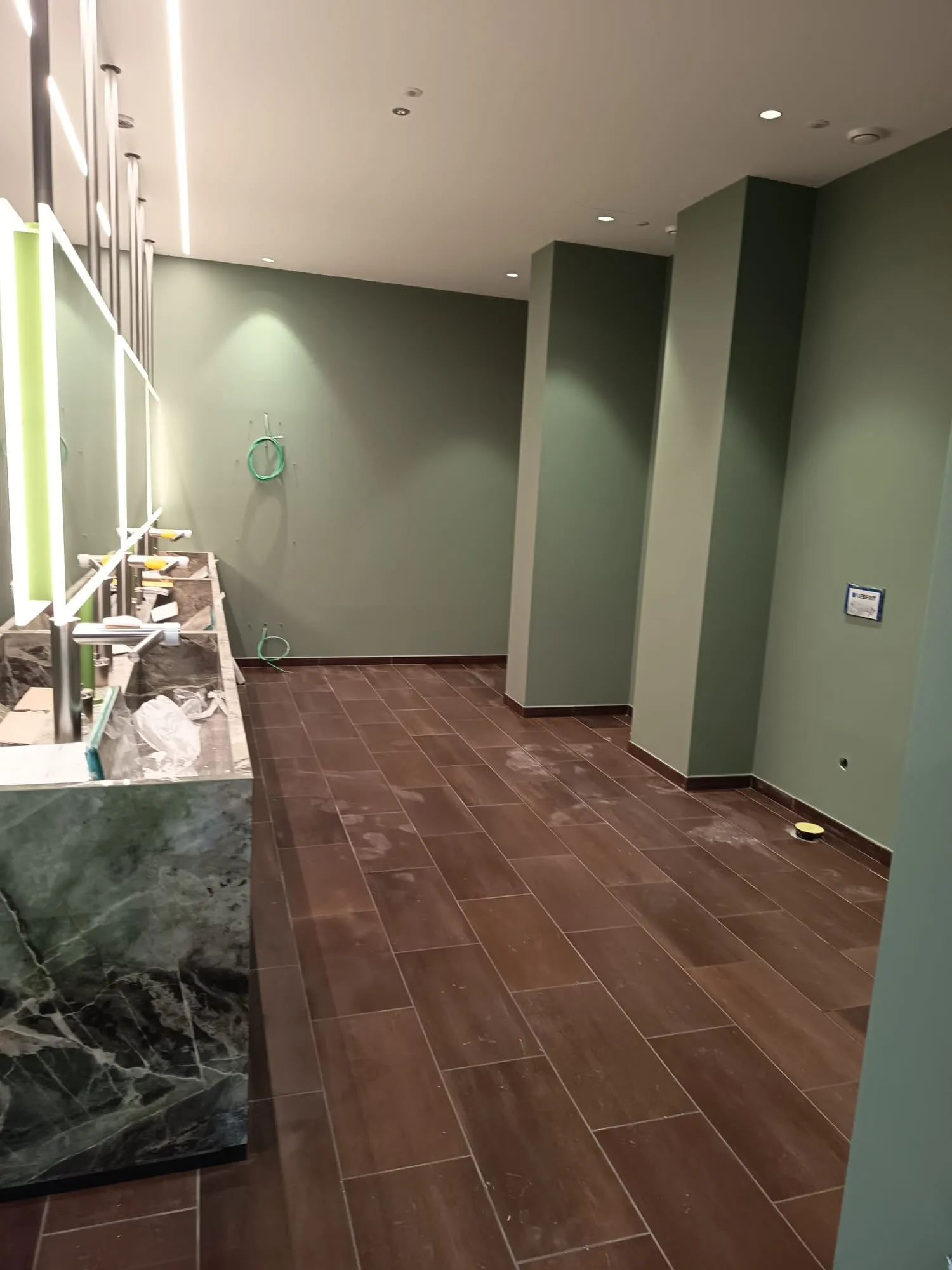 Bagno con pareti color salvia, mobile in marmo verde e illuminazione LED su misura