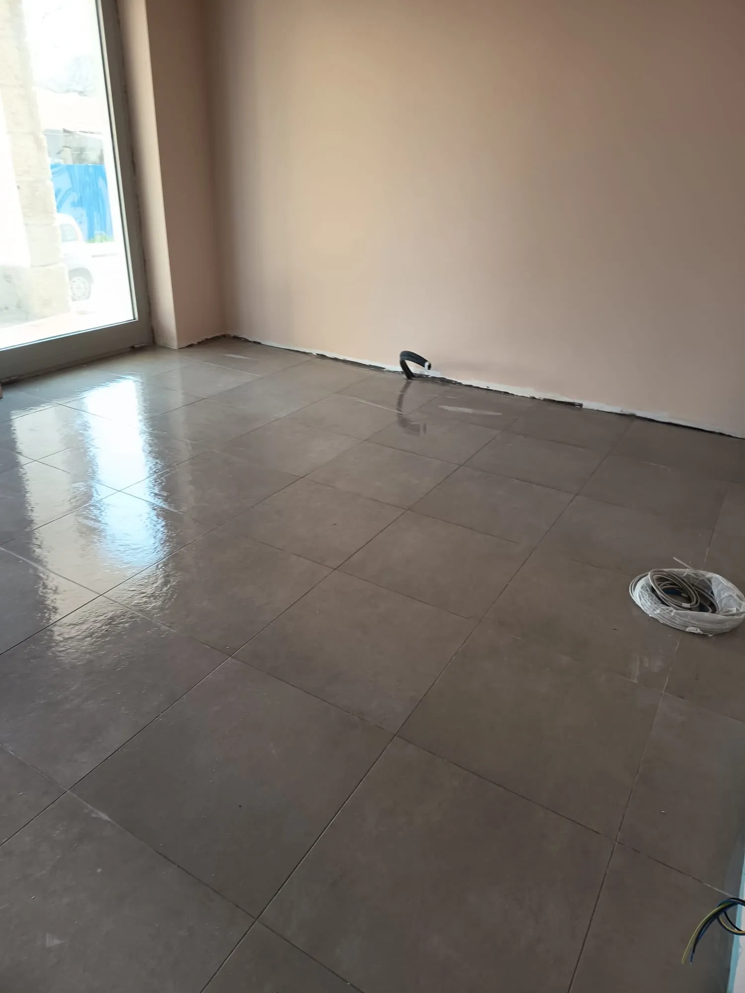 Pavimento in piastrelle smaltate effetto cemento grigio posato in un locale commerciale